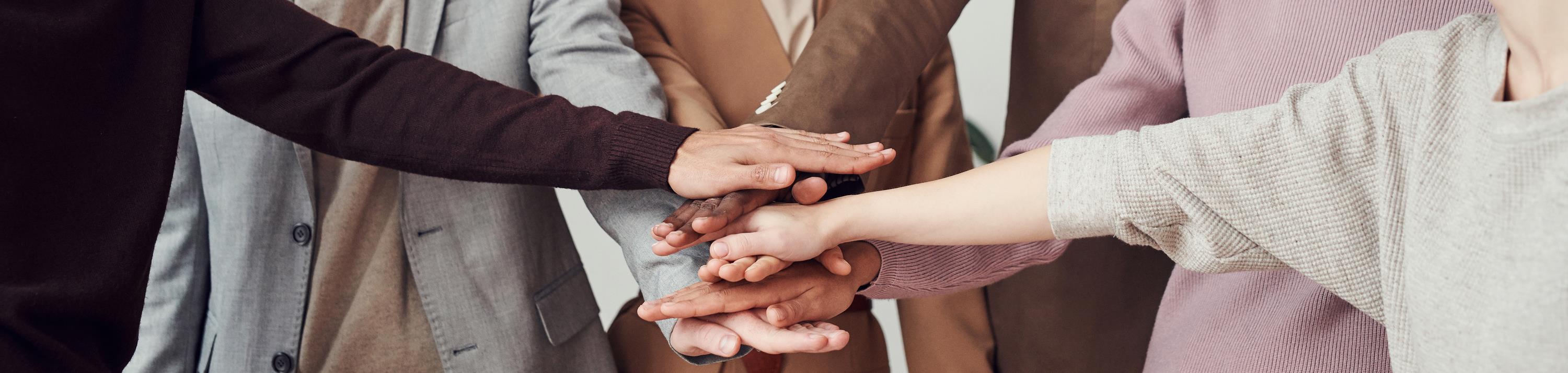 Mains d’une équipe posées les unes sur les autres en signe de solidarité et de respect